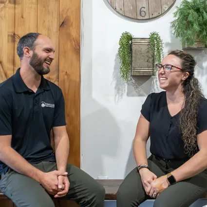 Two chiropractors from Trailhead Family Chiropractic sitting together and smiling in Murrieta, CA