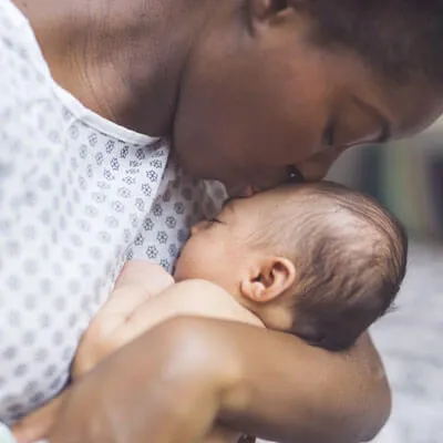 Mother holding and kissing her baby, representing family-centered wellness and gentle infant care support at Trailhead Family Chiropractic
