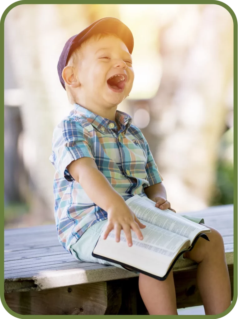 Laughing young boy sitting outdoors, representing healthy childhood development and family wellness supported by chiropractic care