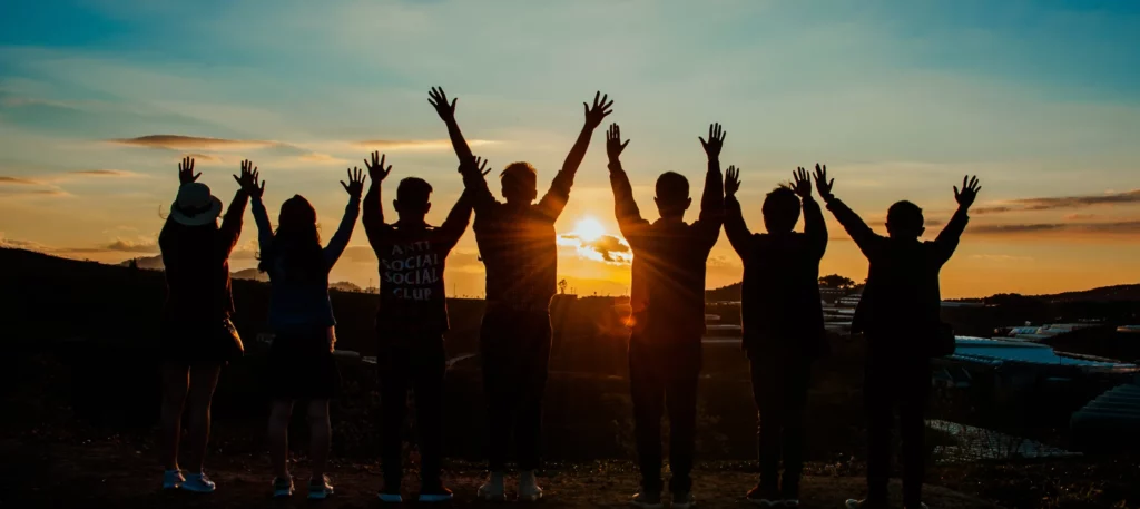 Group of people standing together at sunset, representing community, connection, and whole-body wellness supported by chiropractic care