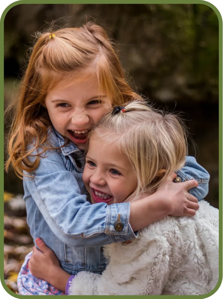 Two young girls hugging and smiling, representing healthy childhood development and family wellness supported by chiropractic care