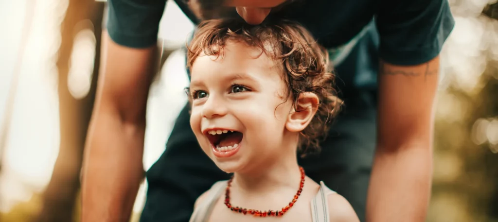 Smiling toddler with a parent, representing healthy childhood development and family wellness supported by chiropractic care