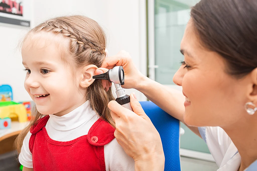 Doctor using an otoscope to examine a young child’s ear during a medical checkup